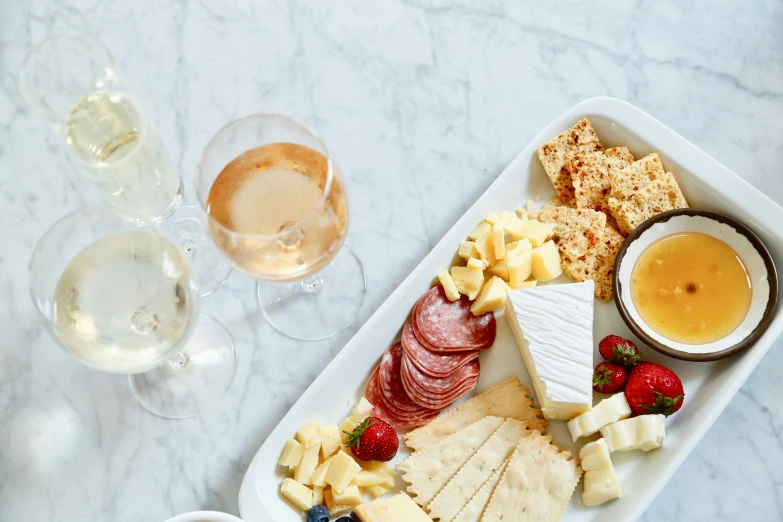 a cheese platter is served with two glasses of wine