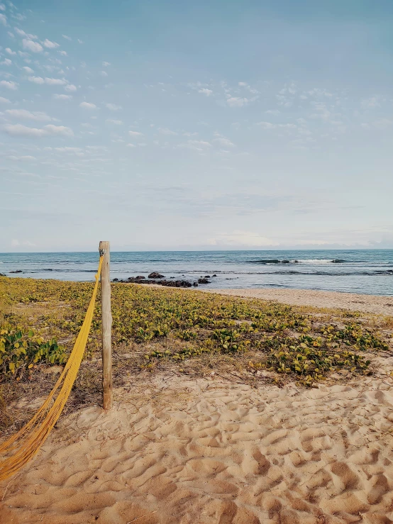 an empty beach with a fence and beach side with waves