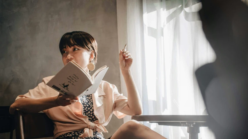 the woman is sitting in a chair holding a book