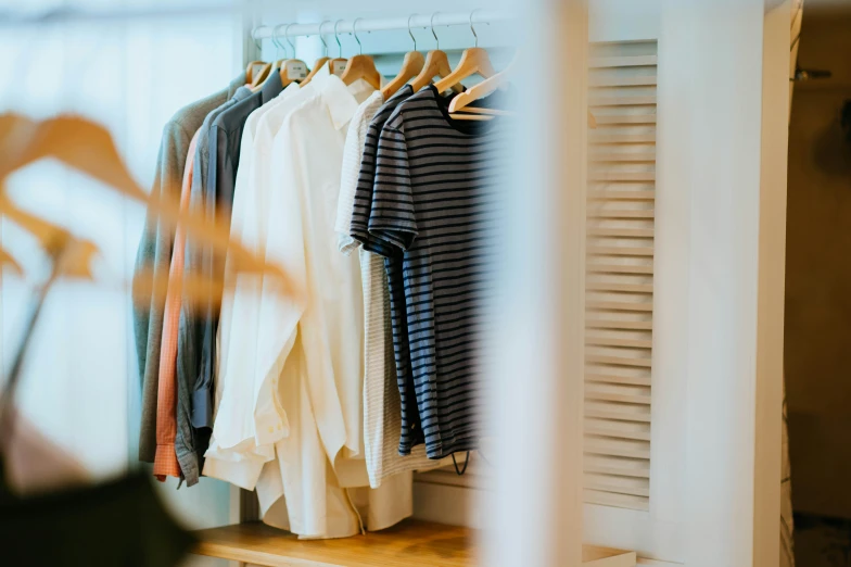 a rack filled with various shirts and pants on hangers