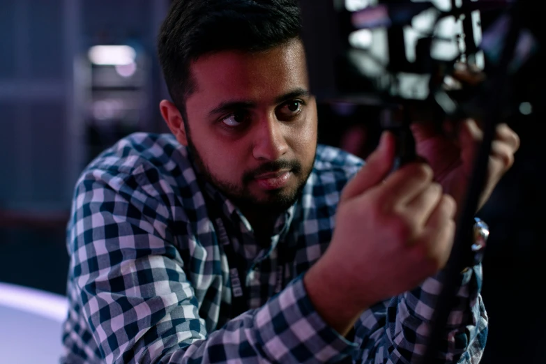 man in checkered shirt holding up electronic device