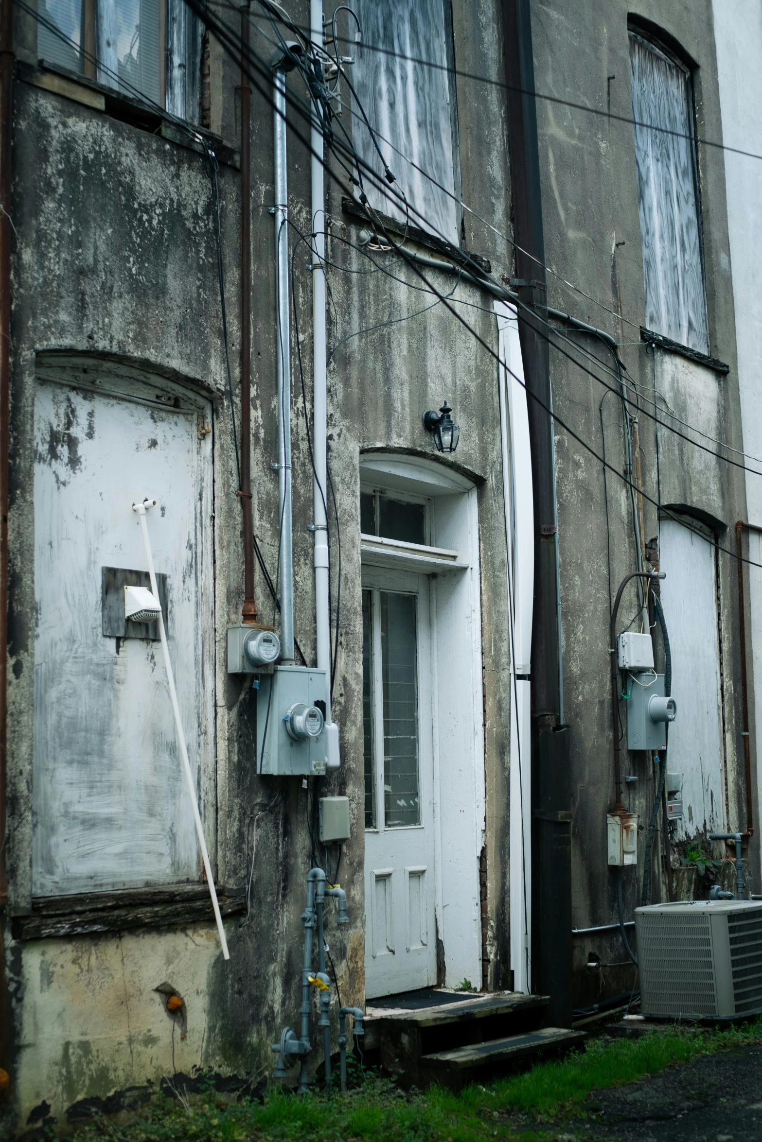 two run down buildings with one door closed and a hose in the air