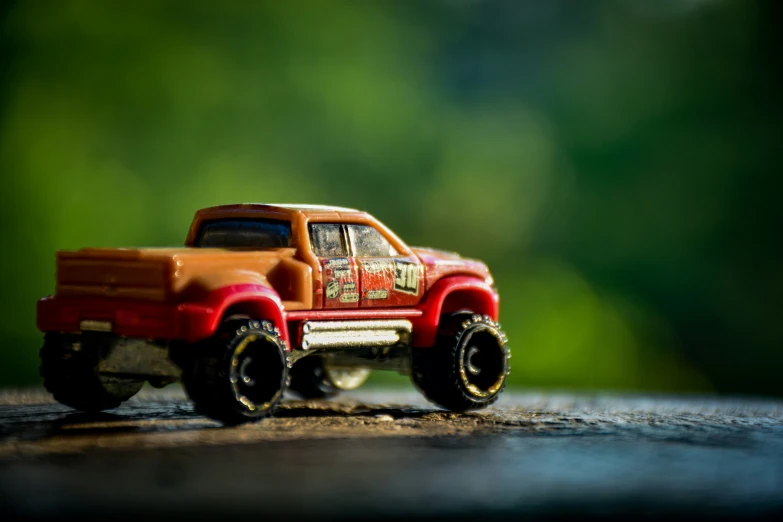 a toy truck sits on the ground in front of a forest