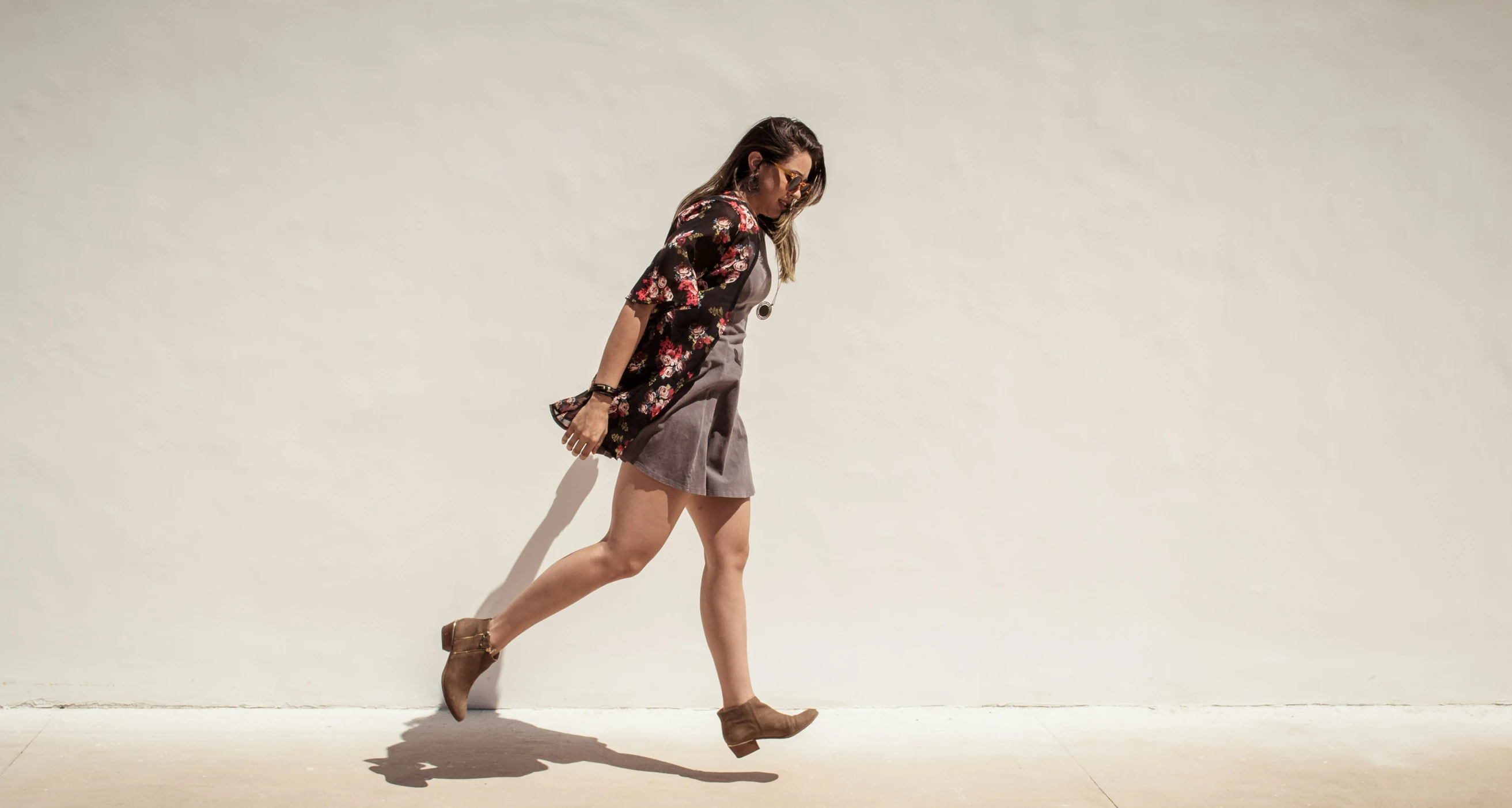 a woman in brown dress walking along a wall