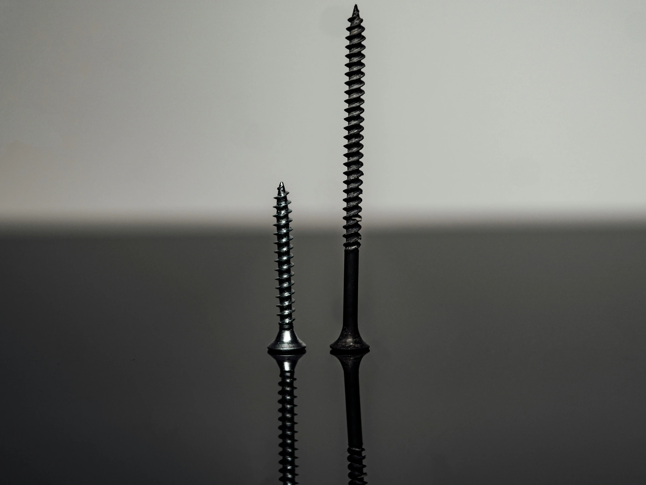 two black and white candles on a table with the reflection off of one candle