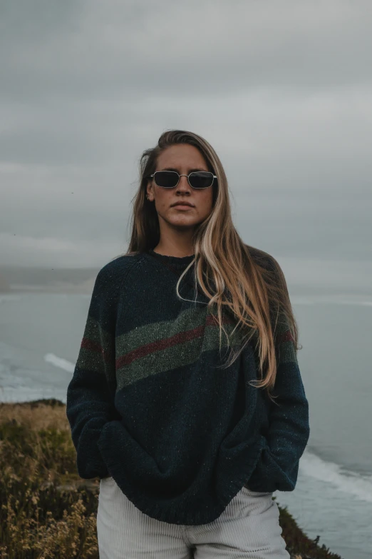 a woman in black sunglasses standing on a hill