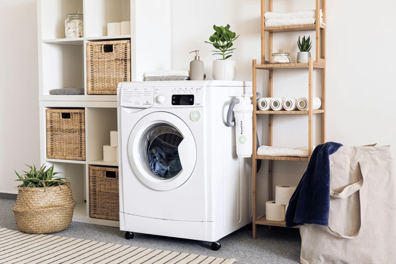 a washer and dryer combo with storage and a ladder behind it