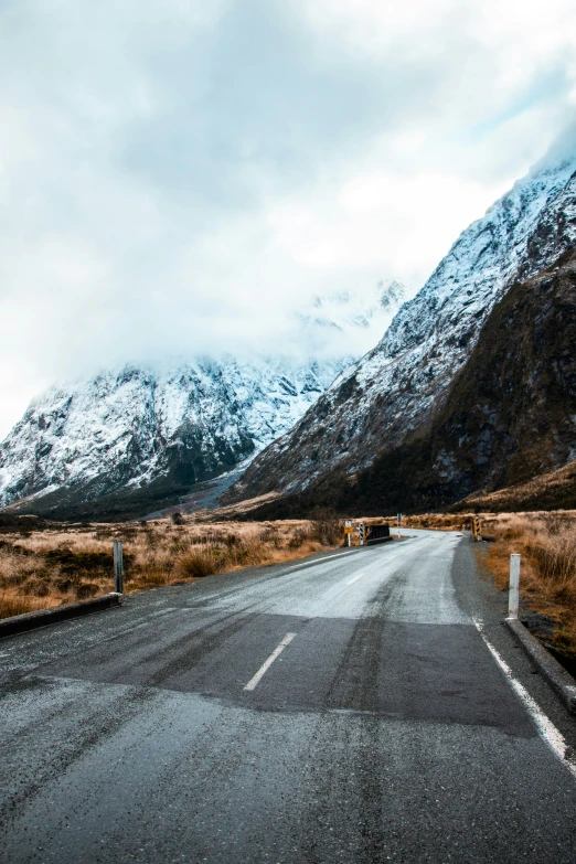 a truck is on a empty road in front of snowy mountains