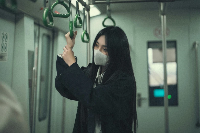 a woman wearing a face mask on top of a subway train