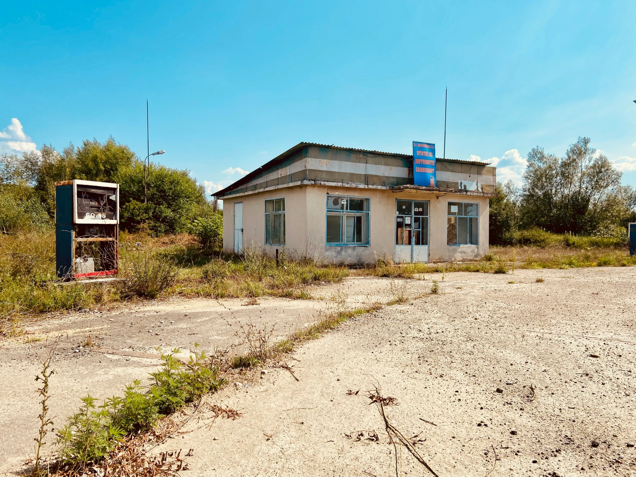 the abandoned building is vacant and deserted with weeds growing out of it