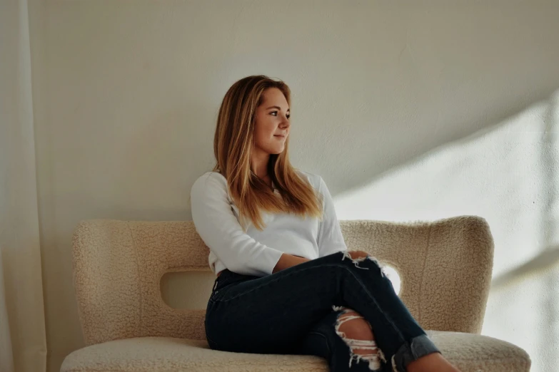 woman posing on a cream colored couch for a picture