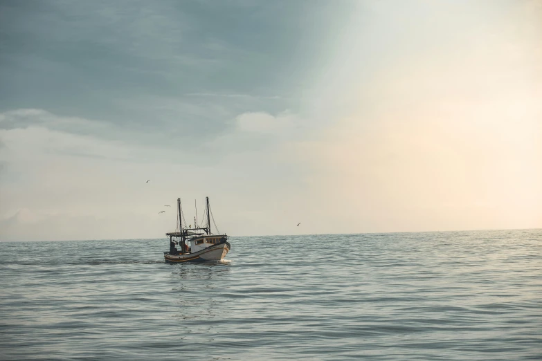 a boat floating off in the ocean on a cloudy day