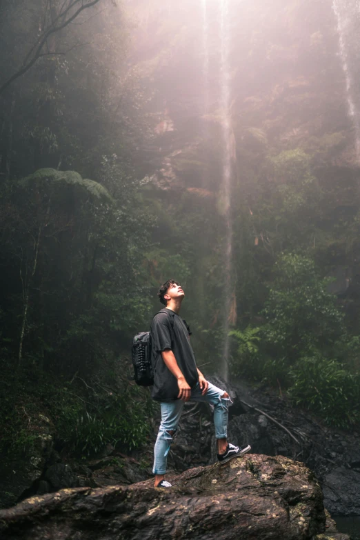 the man looks up into the sky at a waterfall