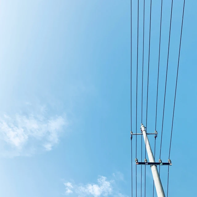 the electrical wires and a telephone pole are under blue sky