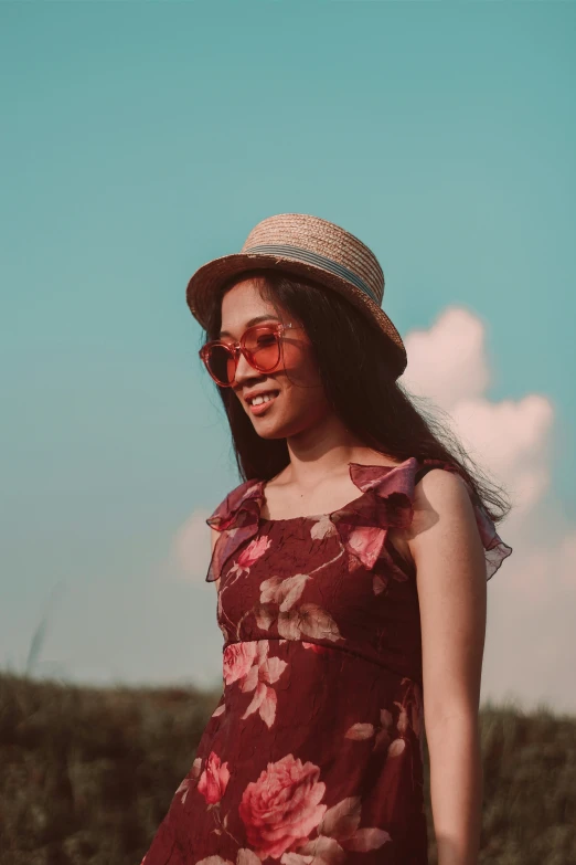 woman wearing red sunglasses and floral dress in field