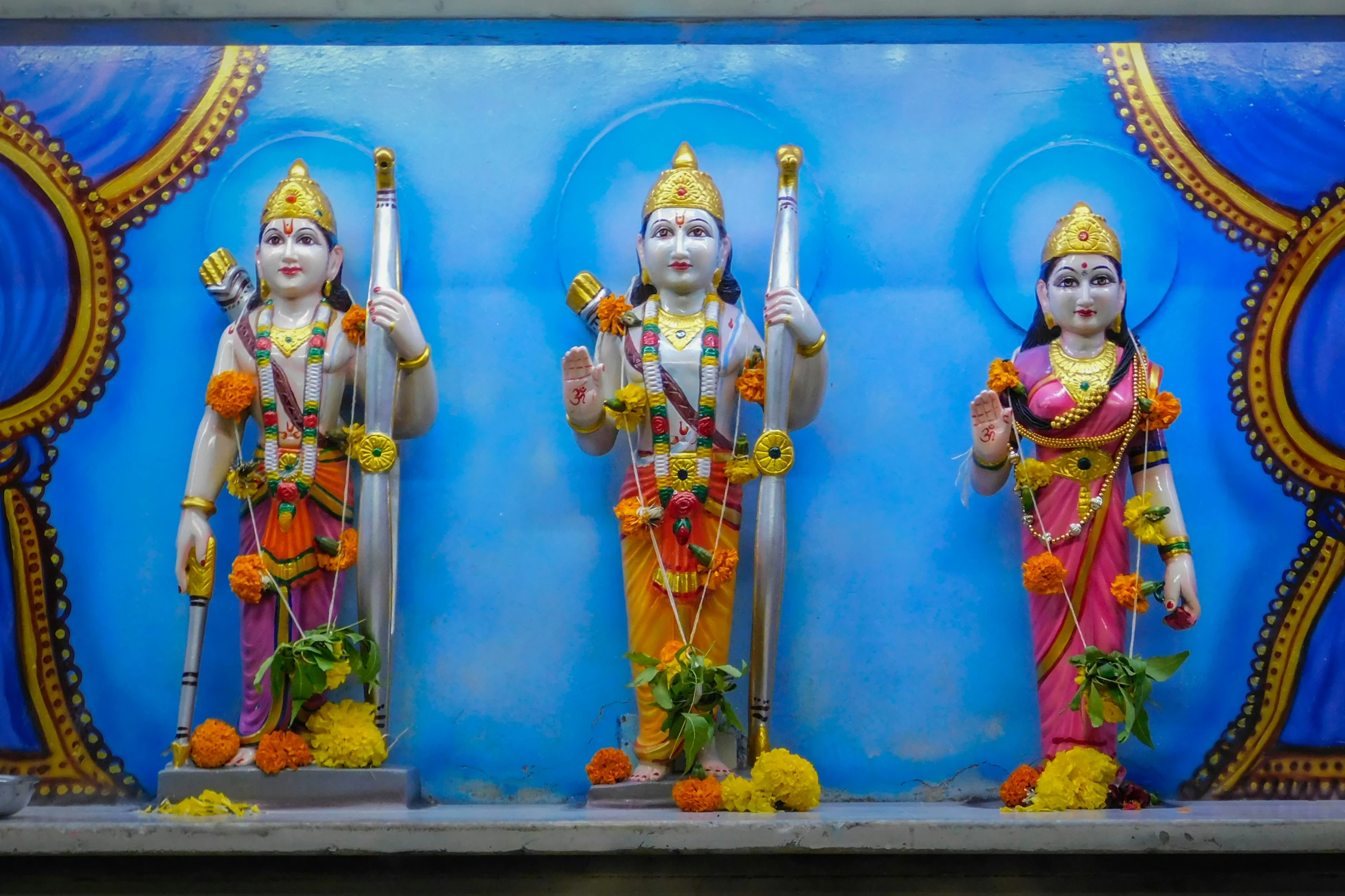 three statues of gods dressed in yellow and orange
