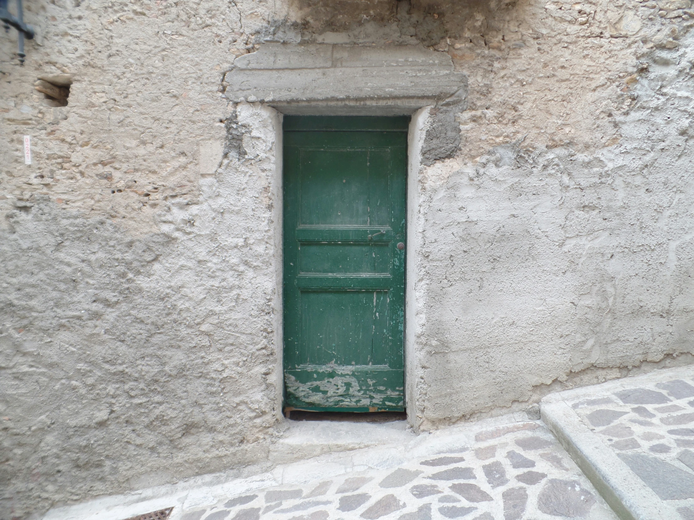 an open green door in front of a grey wall