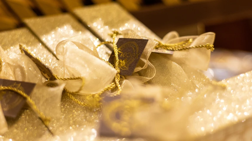 two white and gold gift bags with bows on a table