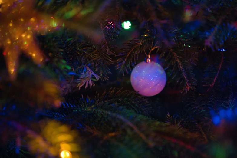 a white ornament hangs from the tip of a christmas tree