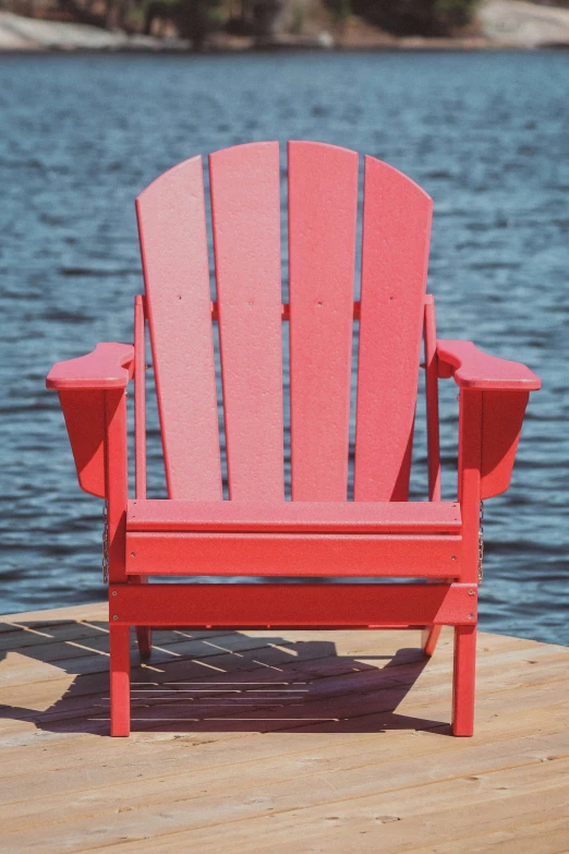 a red wooden adirondack sitting on a pier