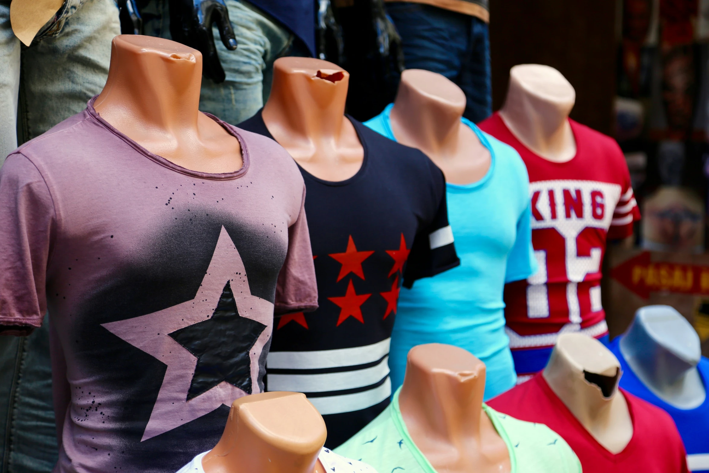 a group of different colored mannequins with t - shirts