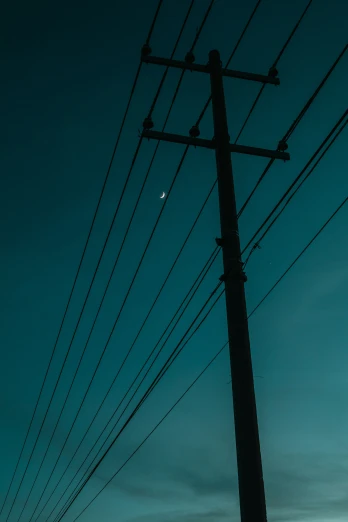 a man in silhouette next to a telephone pole at night