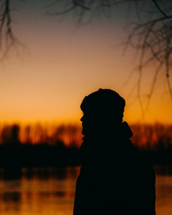 a silhouette of a man in front of water at sunset