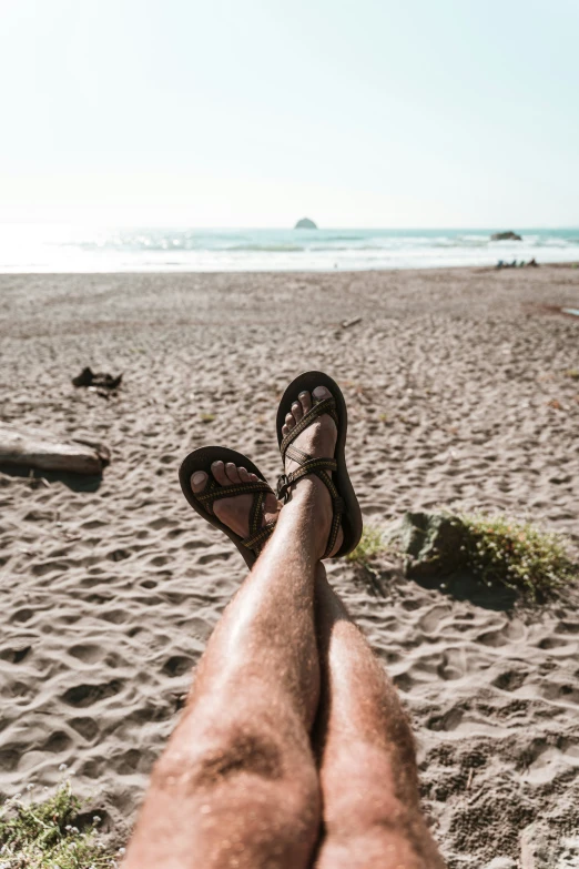 feet in sand with the beach and ocean behind them