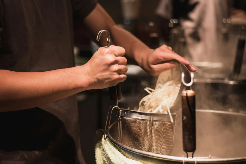 a person using tongs to stir rice noodles