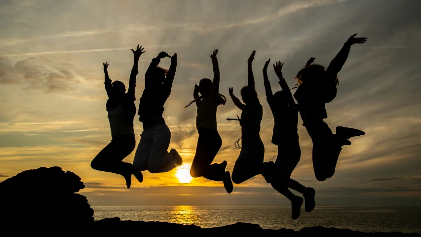 group of people jumping off rock into the sky