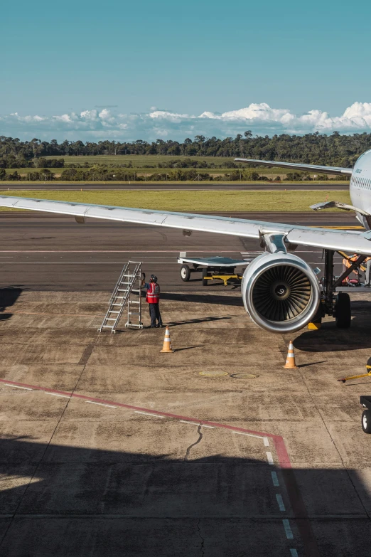 a jet parked on an airport tarmac next to a worker