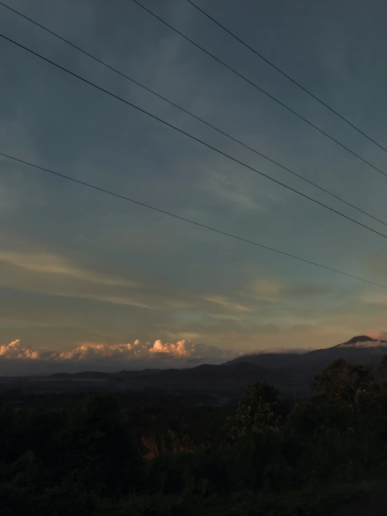 a view of an alpine mountain range at dusk with power lines above