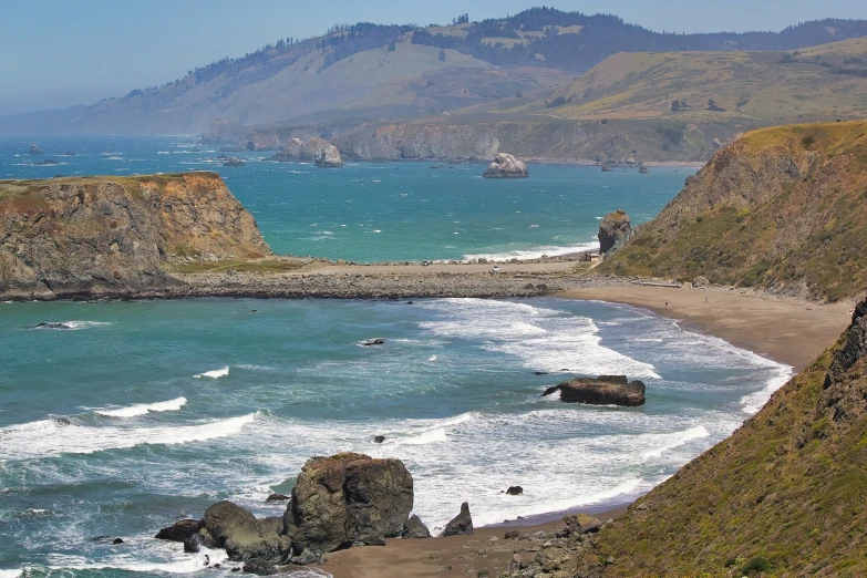 a rocky beach near the sea with mountains in the background