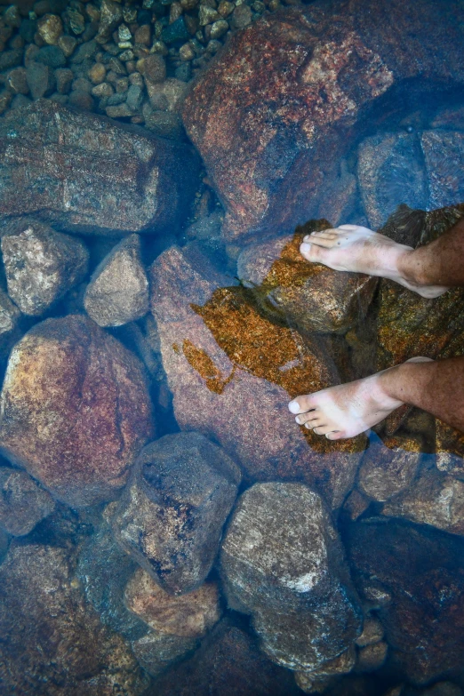 bare feet standing on rock in river bed