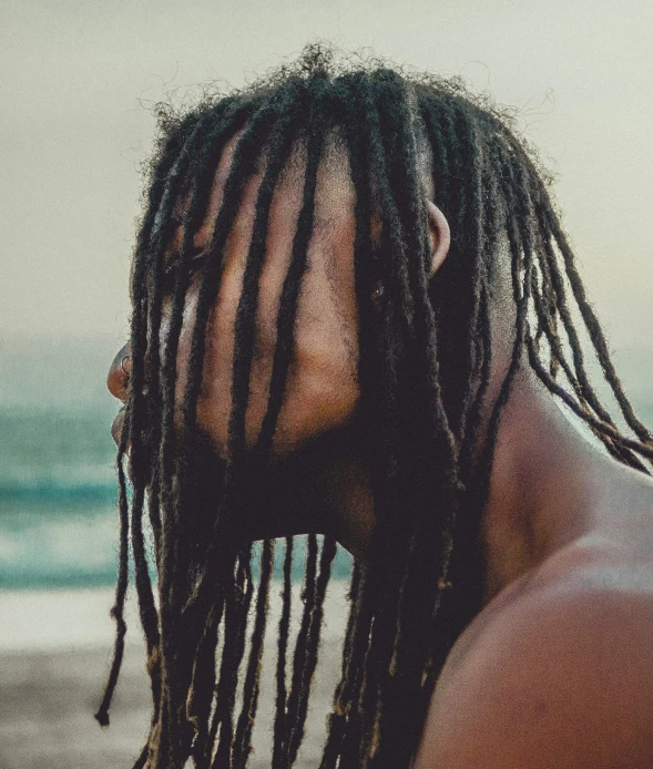 a man with dreadlocks and  on is looking to the sea