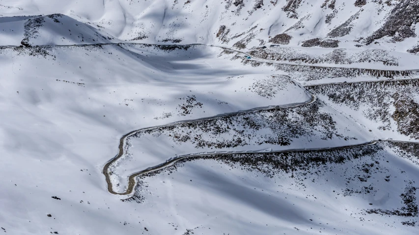 aerial view of snowy hills with a road winding through the snow