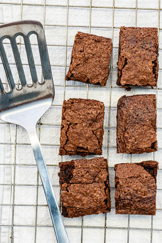 four squares of chocolate brownie on a cooling mat with a cookie scooper