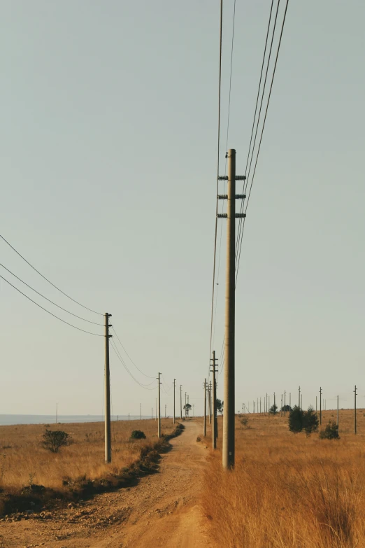 an empty dirt road next to power lines