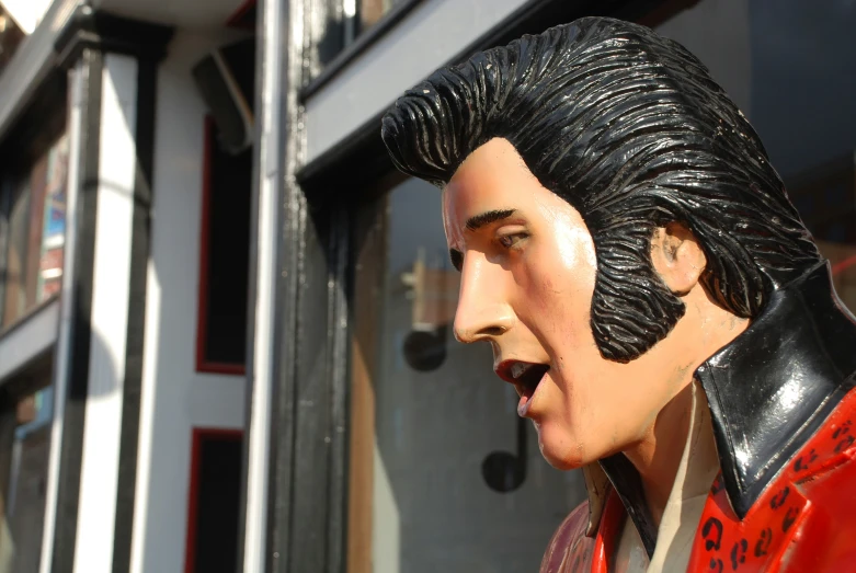 the statue of an elvis in a leather jacket is outside