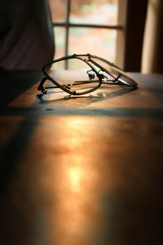 a pair of glasses laying on a desk in front of a window