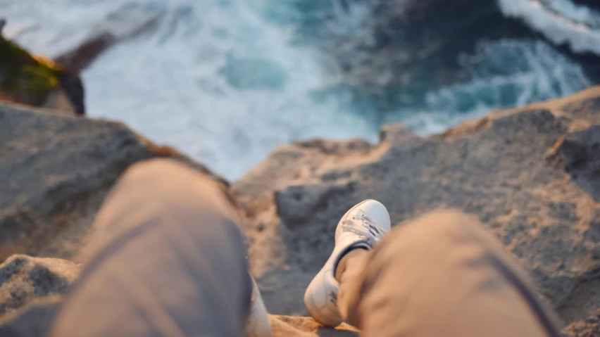 a person sitting on top of a rock near the ocean