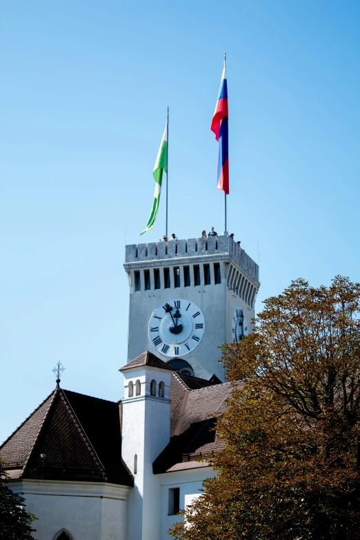 clock tower on the top of a building with flags