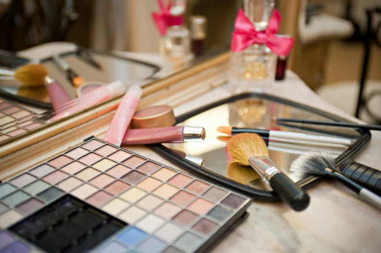 various cosmetics sitting on a table beside a brush