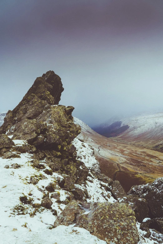 the top of a mountain with a snow - covered area and green plants