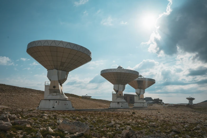 several large satellite dishes sit on the dirt