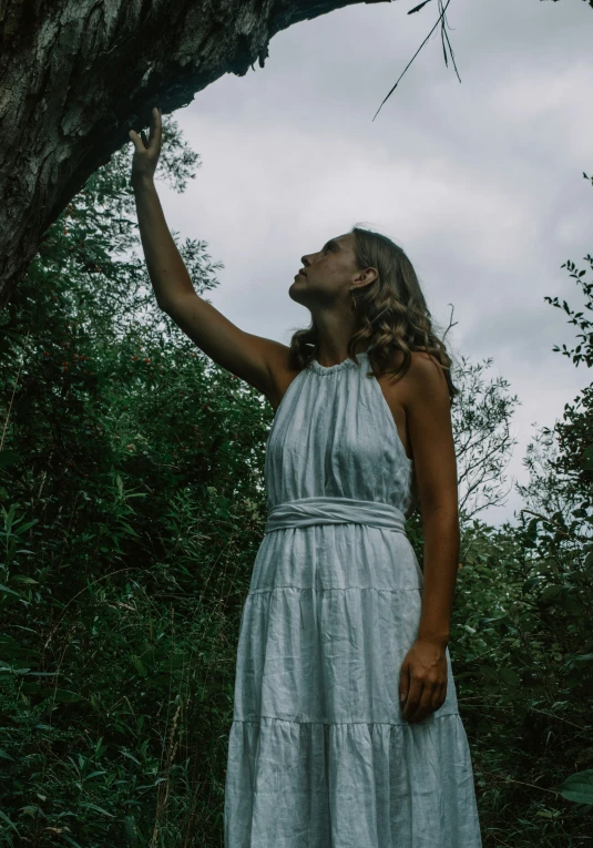 a woman is holding soing up on a nch in a forest