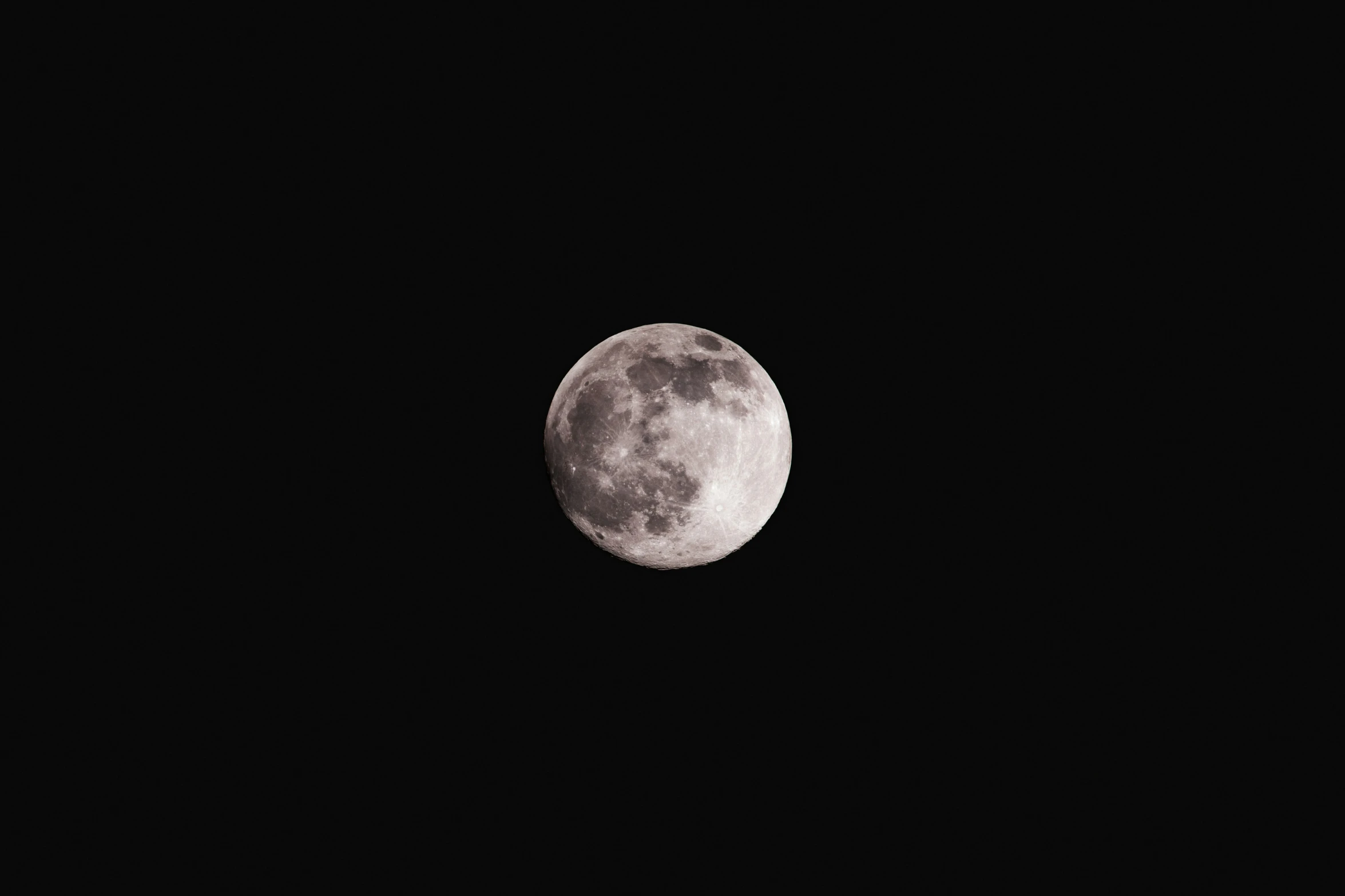 a full moon is seen through the black sky
