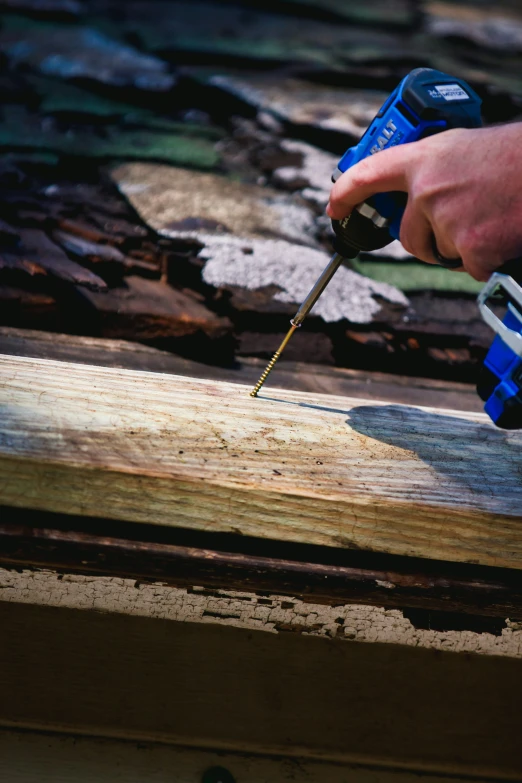 a person uses a nail gun to drill wood planks