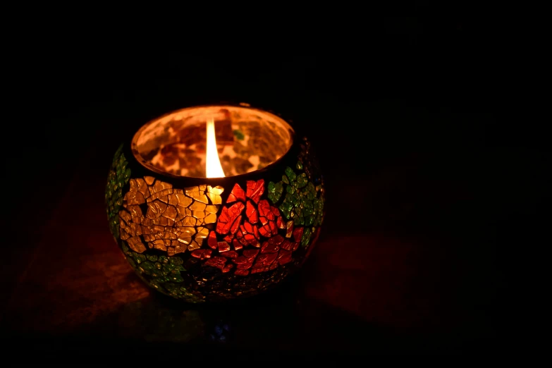 a lit candle in the dark with black background