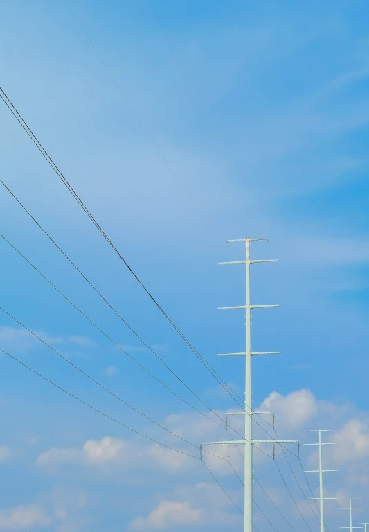 four electric wires above a field under blue skies